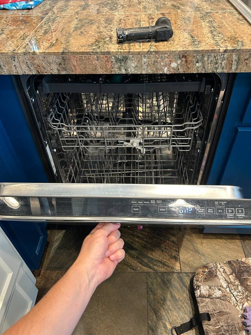 Open built-in kitchen unit with racks visible during a door and latch inspection